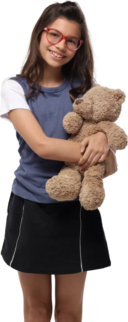 Menina de óculos vermelhos sorrindo e abraçando um urso de pelúcia