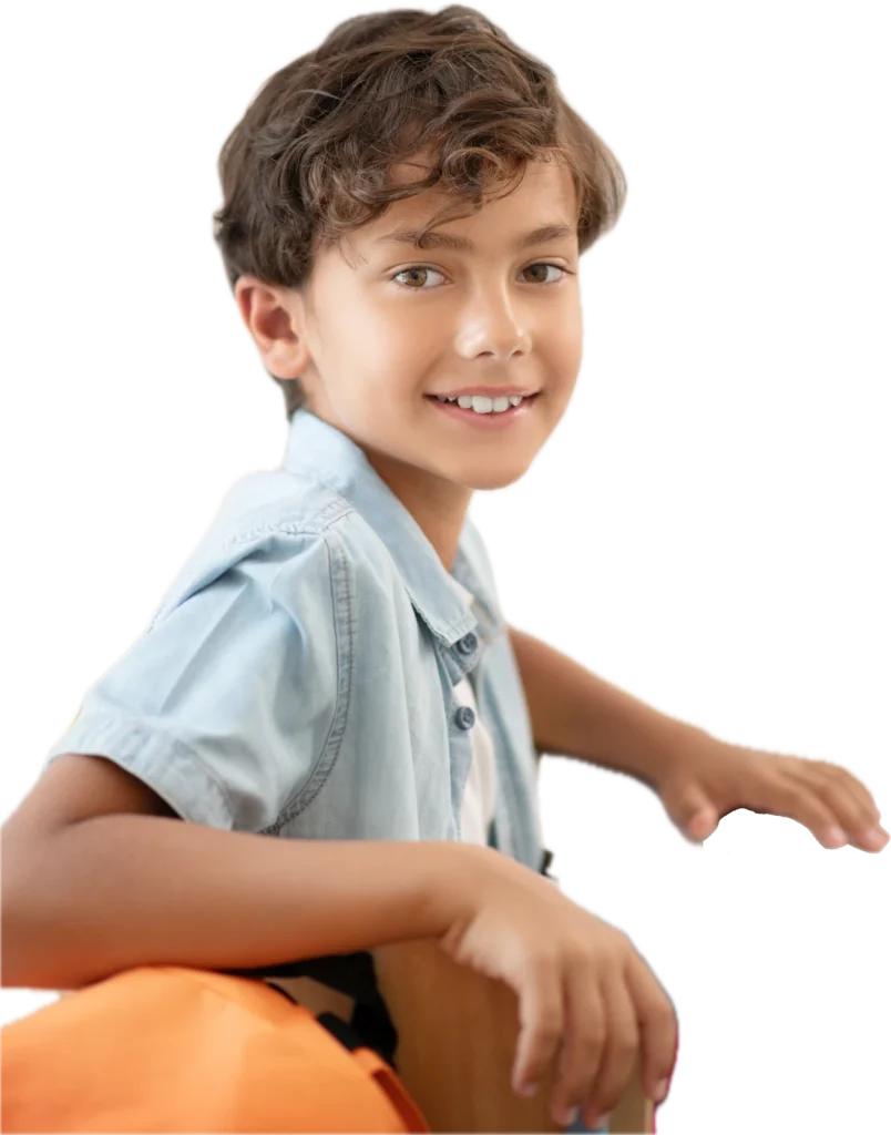 Menino de camisa jeans sorrindo, sentado na carteira da sala de aula